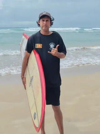 Nishantha with his surfboard on the beach
