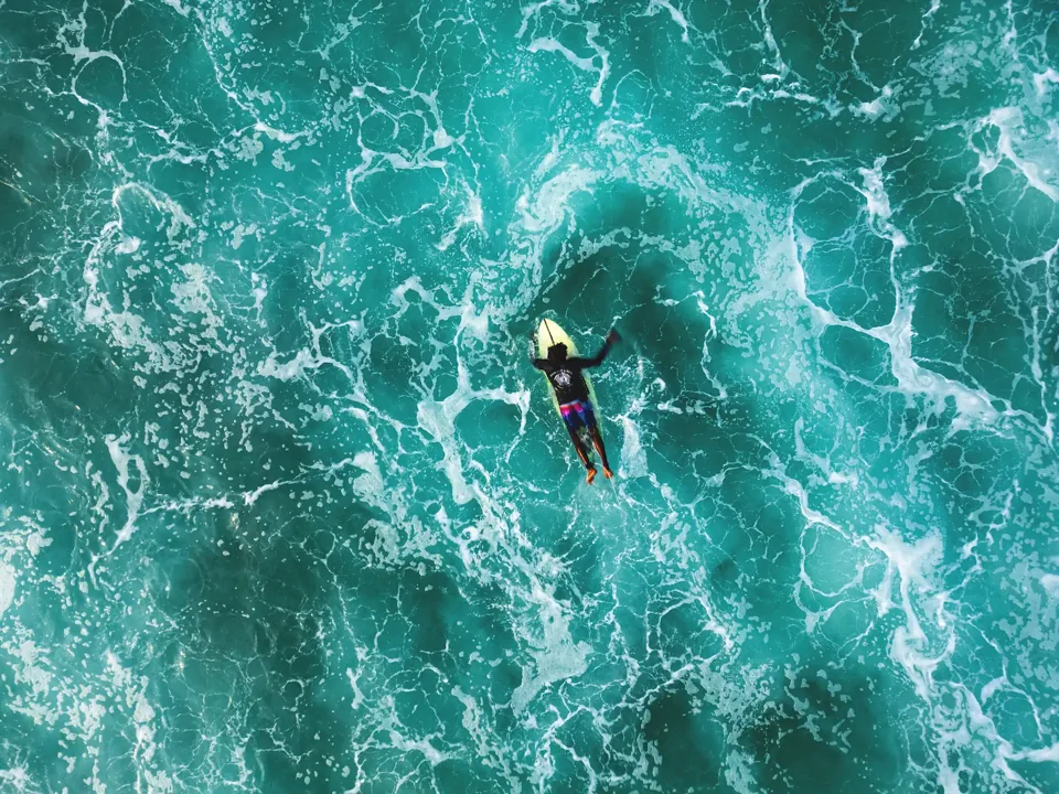 A surfer captured from above in turquoise Kabalana waves